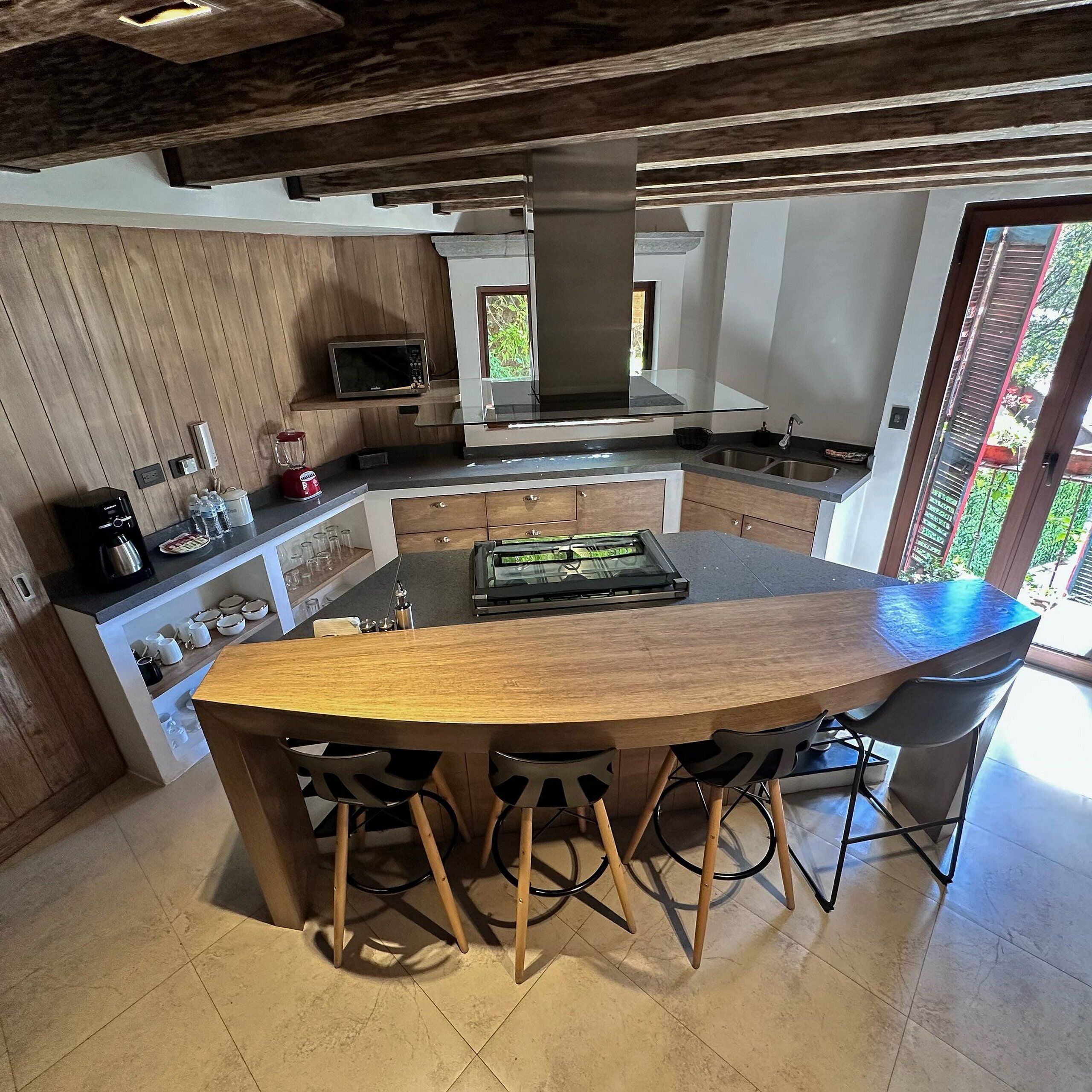 Een moderne keuken met een centraal eiland, barstoelen, een magnetron en een groot fornuis.