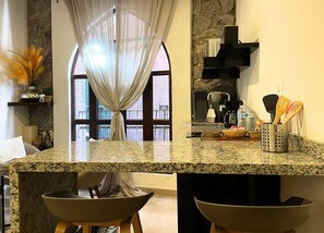Una cocina con encimeras de granito, cafetera y utensilios en un organizador.