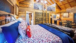Une chambre confortable dans un chalet en rondins, avec un lit, une petite kitchenette et un balcon.