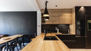 A modern kitchen with a wooden island, black cabinetry, and stainless steel appliances.