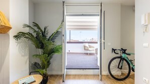 Un apartamento moderno con puerta corrediza a un balcón, una bicicleta y una planta en maceta.
