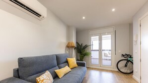 Una sala moderna con un sofá gris, una planta y una bicicleta.