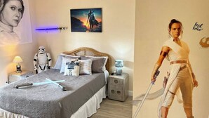 Une chambre à coucher avec un lit, des oreillers, une affiche de Star Wars, un autocollant mural sur le thème de Star Wars et une figurine de Star Wars.