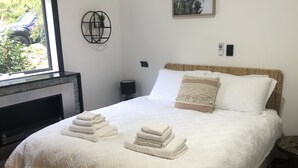 A bedroom with a large bed, a fireplace, and a window with a view of greenery.