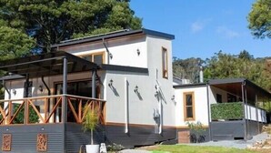 A modern two-story house with a covered porch, large windows, and a small garden area.