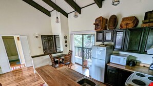Une cuisine avec un plancher en bois, un îlot central doté de tabourets, un réfrigérateur, un four à micro-ondes et une cuisinière.