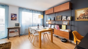 Un soggiorno moderno con zona pranzo, mobili in legno e una libreria con diversi oggetti.