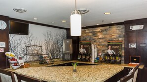 A bar area with granite countertops, a large island, and seating. There are two bar stations with stools, a television mounted on the wall, and a stone wall with a fireplace. - Pool and Hot Tub. Near University of North Dakota (Grand Forks)