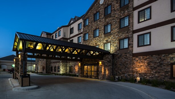 A hotel entrance with a covered walkway and stone facade. - Pool and Hot Tub. Near University of North Dakota (Grand Forks)