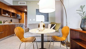 Eine moderne Küche mit Holzausstattung, einem runden Esstisch mit zwei Stühlen, einem Sofa und einer Stehlampe.