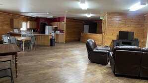 Amplia sala de estar con piso de madera, una mesa de comedor con sillas, un sofá y un televisor.