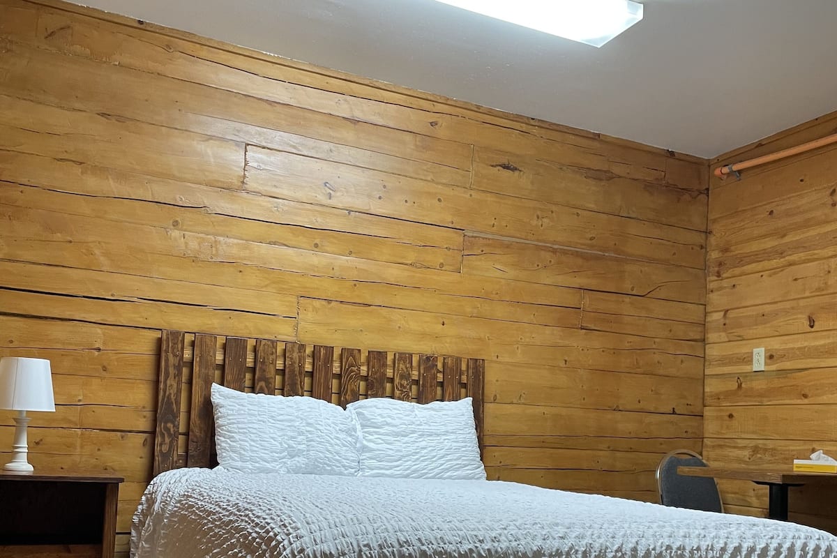 A wooden-paneled room with a bed, a nightstand, and a table.