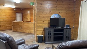 Habitación con paneles de madera, sillones de cuero, un televisor sobre un mueble y una señal de salida.