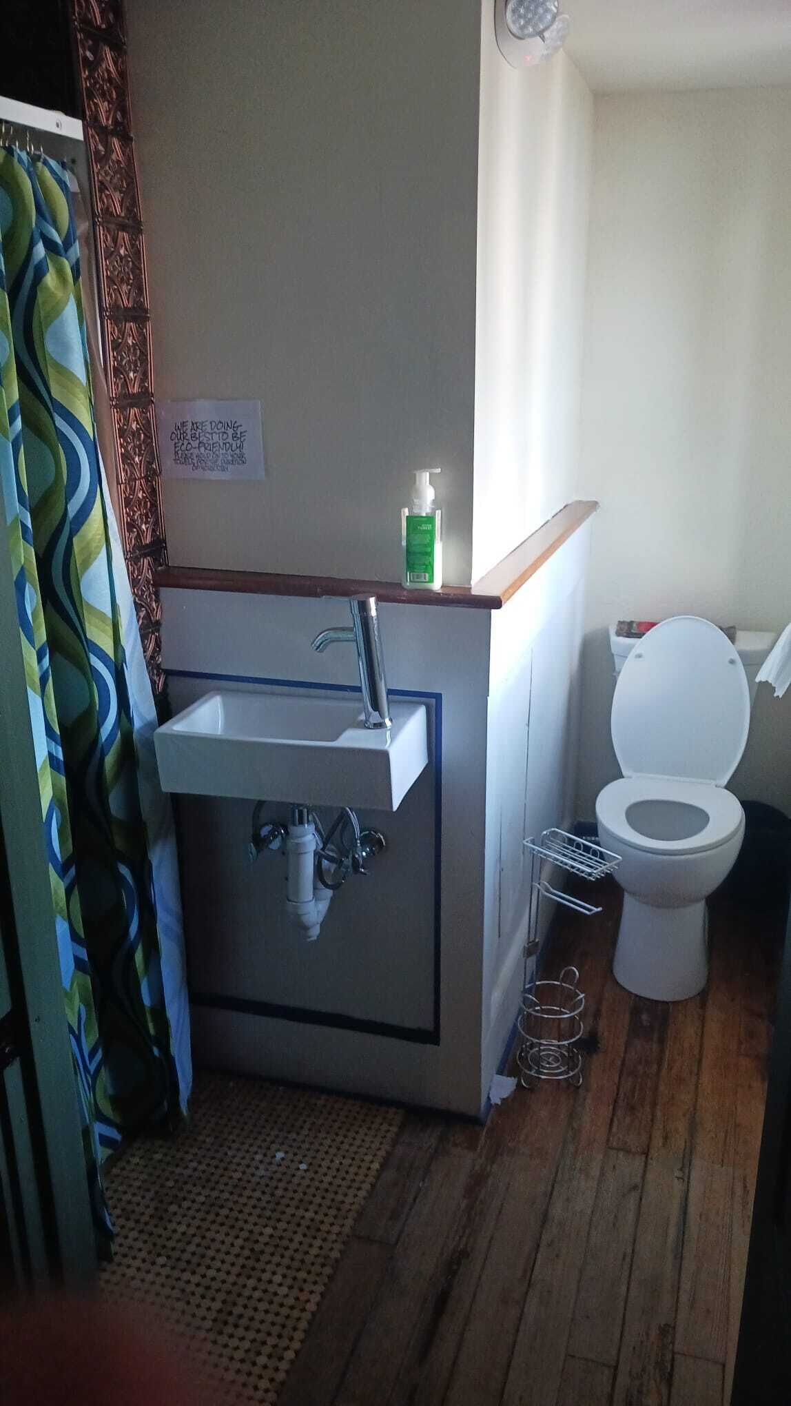 Une petite salle de bain avec un lavabo, des toilettes et un rideau de douche.