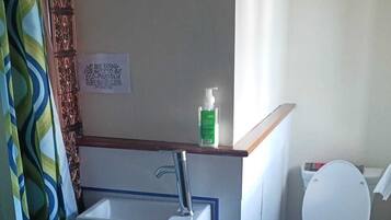 Une petite salle de bain avec un lavabo, des toilettes et un rideau de douche.