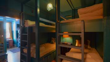 Habitación tipo dormitorio con literas, un escritorio y una lámpara.