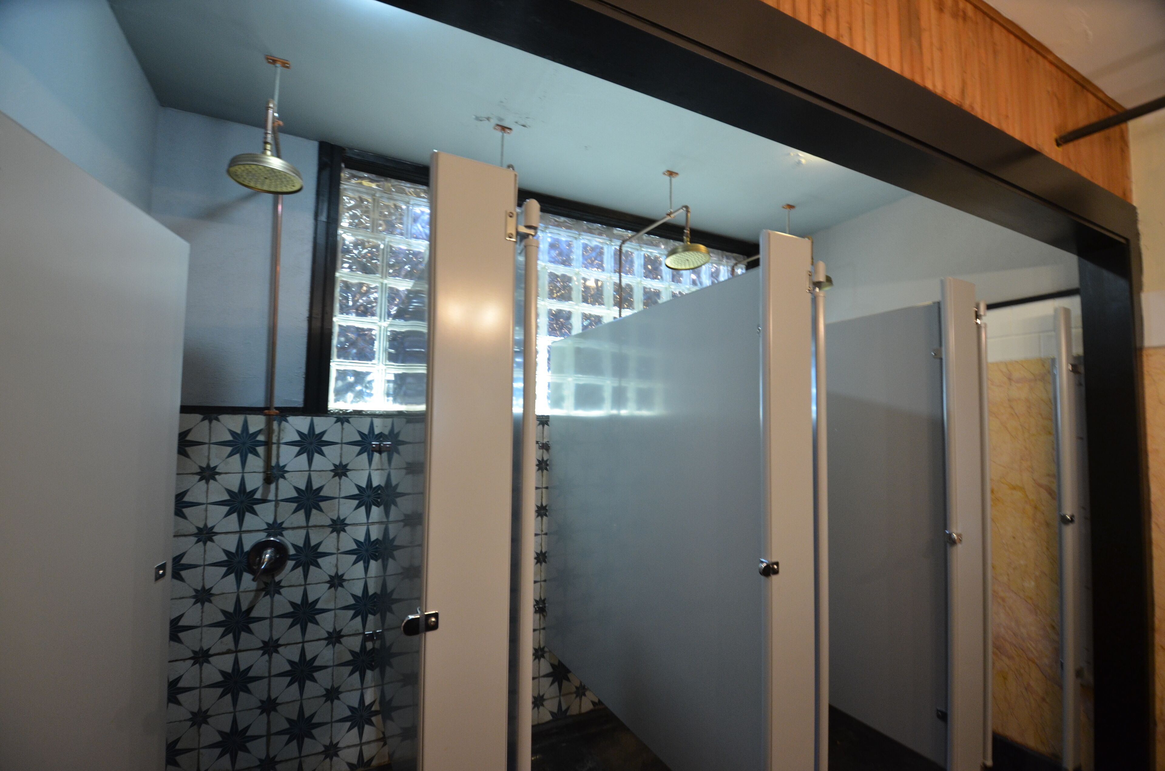 A bathroom with a tiled wall, a shower, and a window.