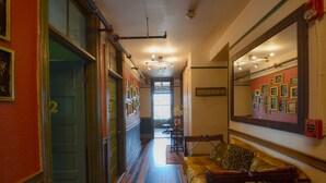A hallway with a wooden bench, a fire alarm, and framed pictures on the walls. - Michie Hostel (Providence)