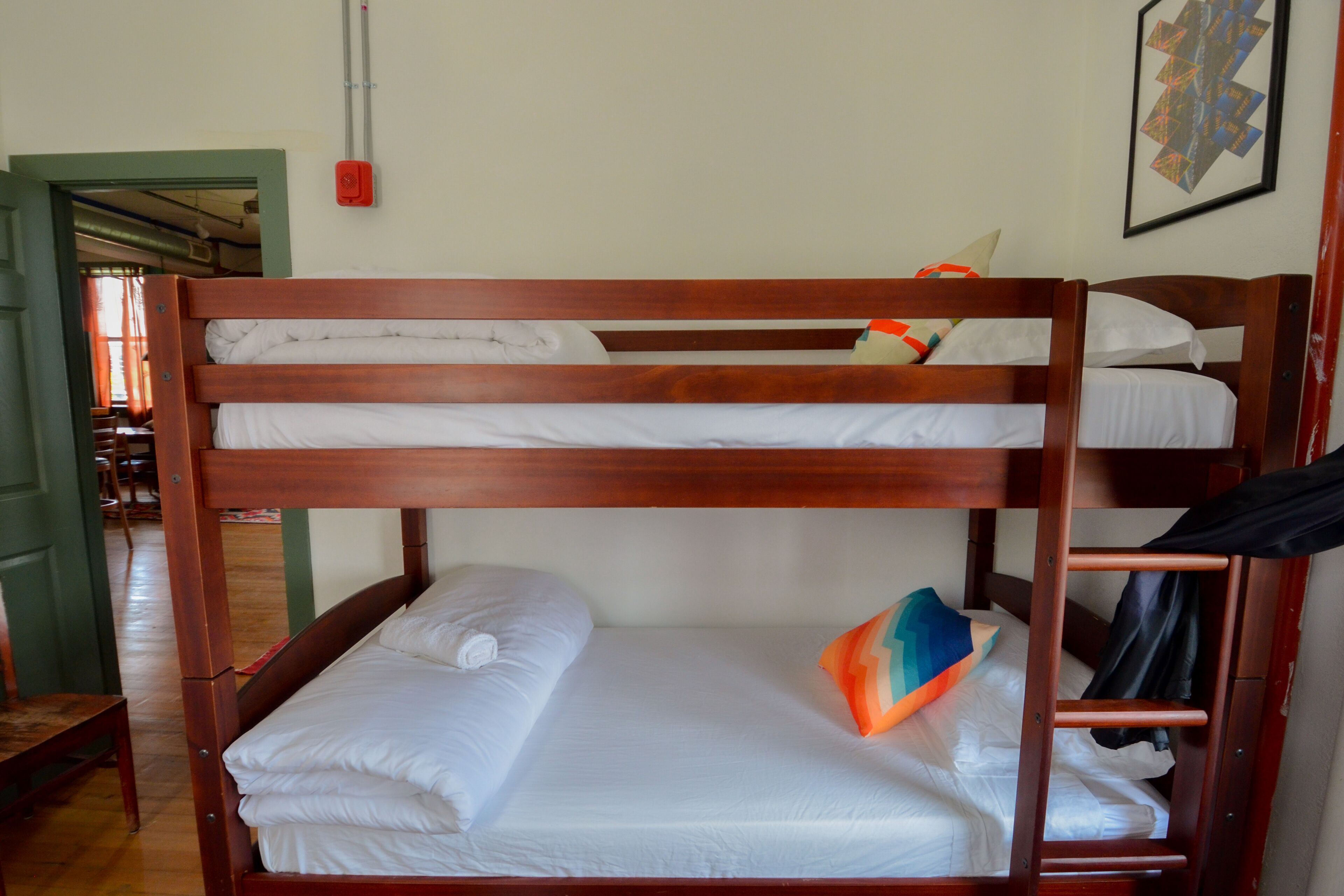 A bunk bed with white bedding and a colorful pillow.