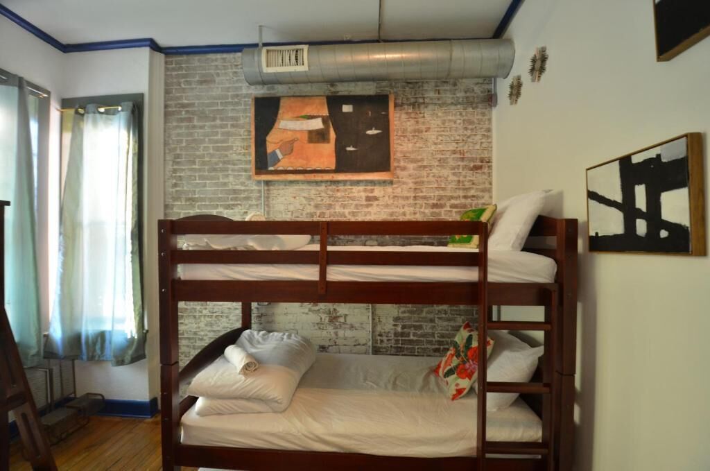 A bunk bed room with a brick wall and a painting.