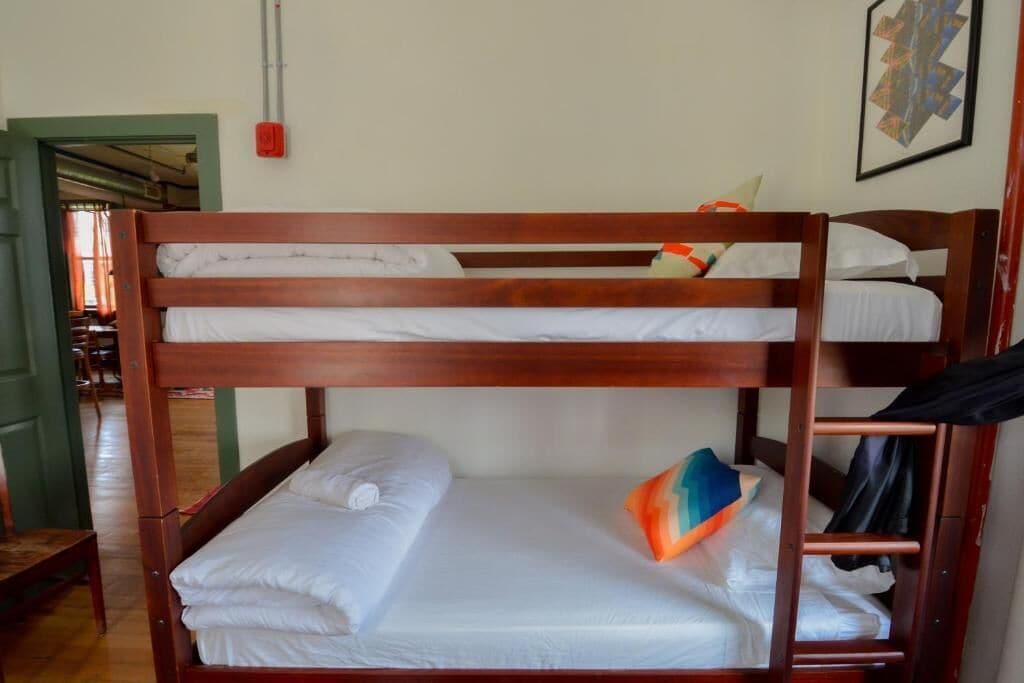 Un lit superposé avec une literie blanche et un coussin coloré.