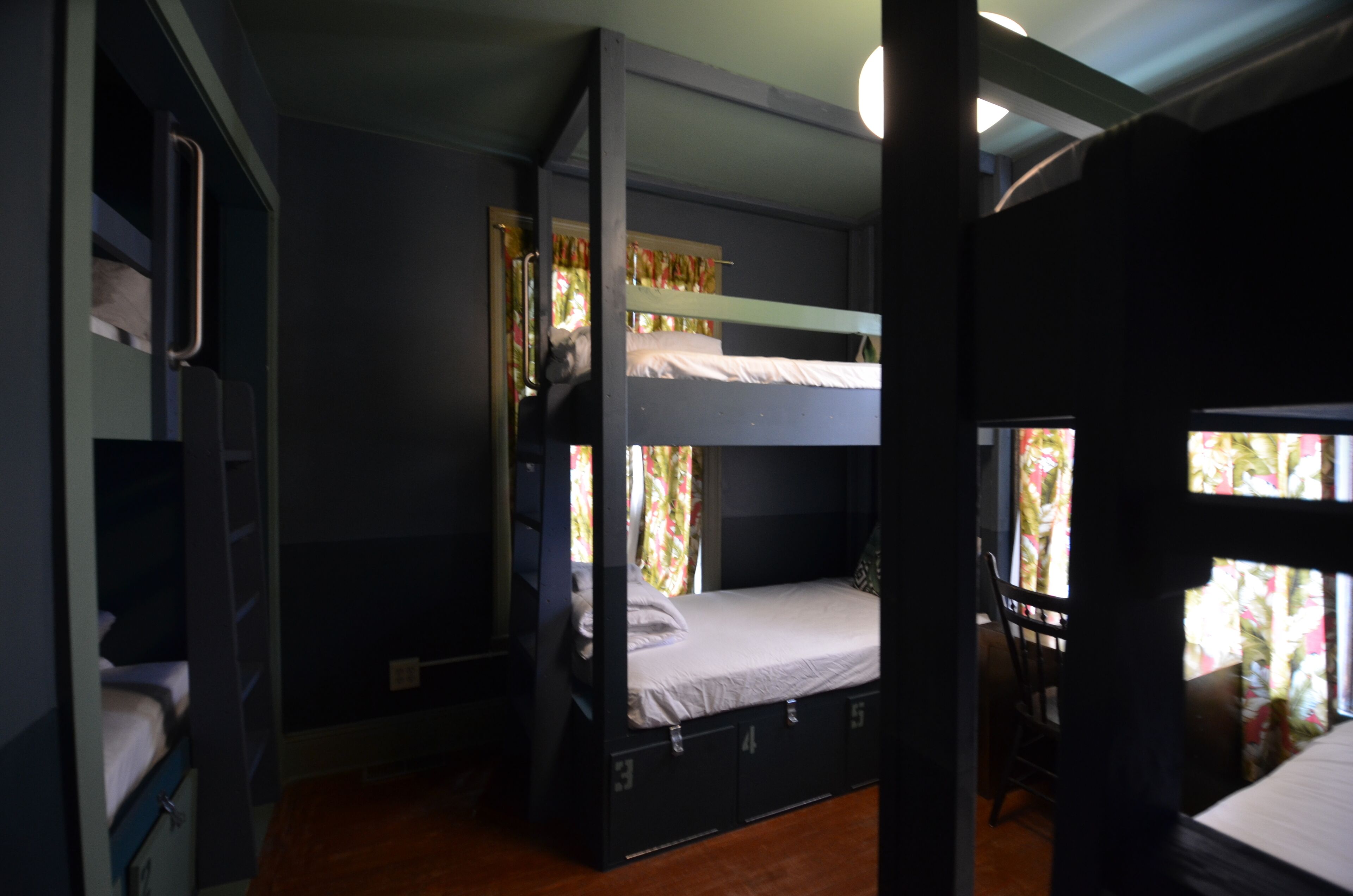 A bunk bed room with a window, a chair, and a door.