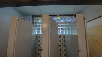 Ein Badezimmer mit gefliestem Wandbereich und einem Fenster über der Duschkabine.