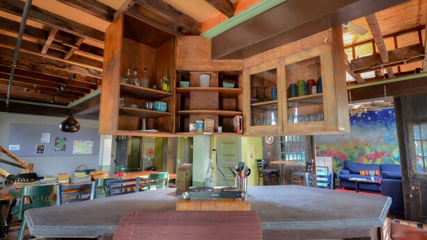A rustic interior with wooden shelves, a dining table, and a mural on the wall. - Michie Hostel (Providence)