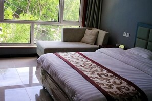 Un dormitorio con una cama grande, un sofá, una ventana con vistas a zonas verdes y una mesita de noche.
