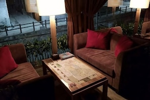 A cozy seating area with a sofa and chairs, a table with a map, and a view of the street outside. - Beijing Dongshanyuan Hotel (Beijing)