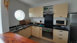 Een moderne keuken met een houten aanrecht, een inbouwoven, een magnetron en een roestvrijstalen koelkast.