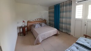Een slaapkamer met een bed, nachtkastje, gordijnen en een airconditioning.