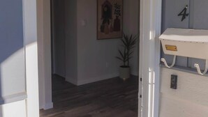 A hallway with a wooden floor, a white door frame, and a small potted plant.
