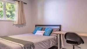A bedroom with a bed, a desk, and a chair.