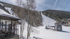 A ski resort with a building featuring a balcony and a ski lift area.