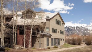 A two-story building with a sloped roof, a garage, and a pathway leading to a mountain view.