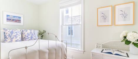 Une chambre à coucher avec un lit, une table de chevet et une fenêtre.
