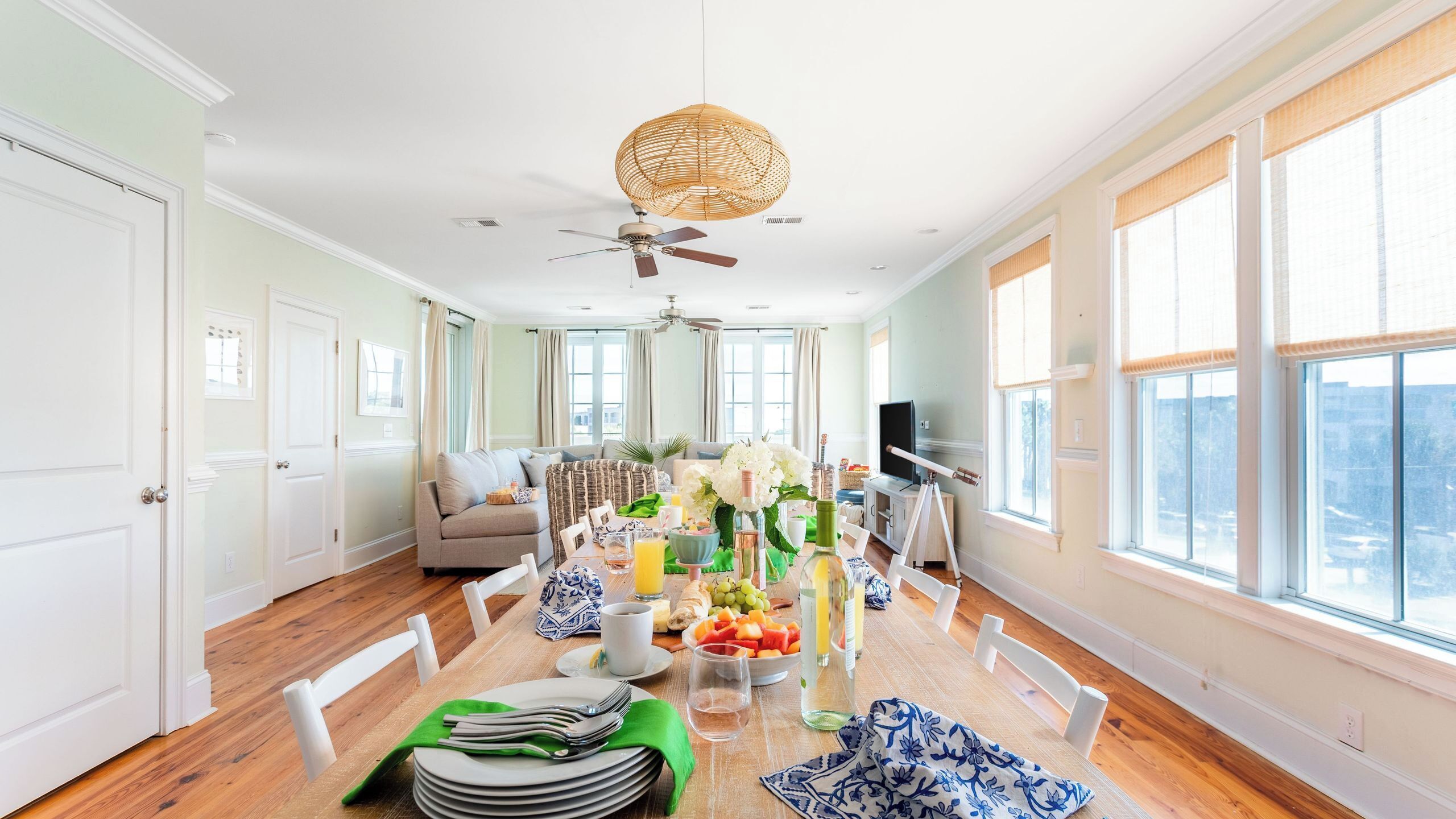 A spacious living area with a dining table set for breakfast, a sofa, and a ceiling fan.