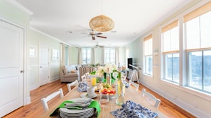 Un vaste espace de vie comprenant une table à manger dressée pour le petit-déjeuner, un canapé et un ventilateur de plafond.