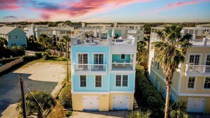 A coastal residential area with multi-story buildings, balconies, and palm trees. - Sea Shell by Avantstay Breezy Beachside Getaway w/ Rooftop Deck & 6 BRs (Isle of Palms)