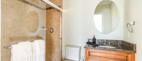 Un baño con ducha, inodoro, lavamanos y tocador.