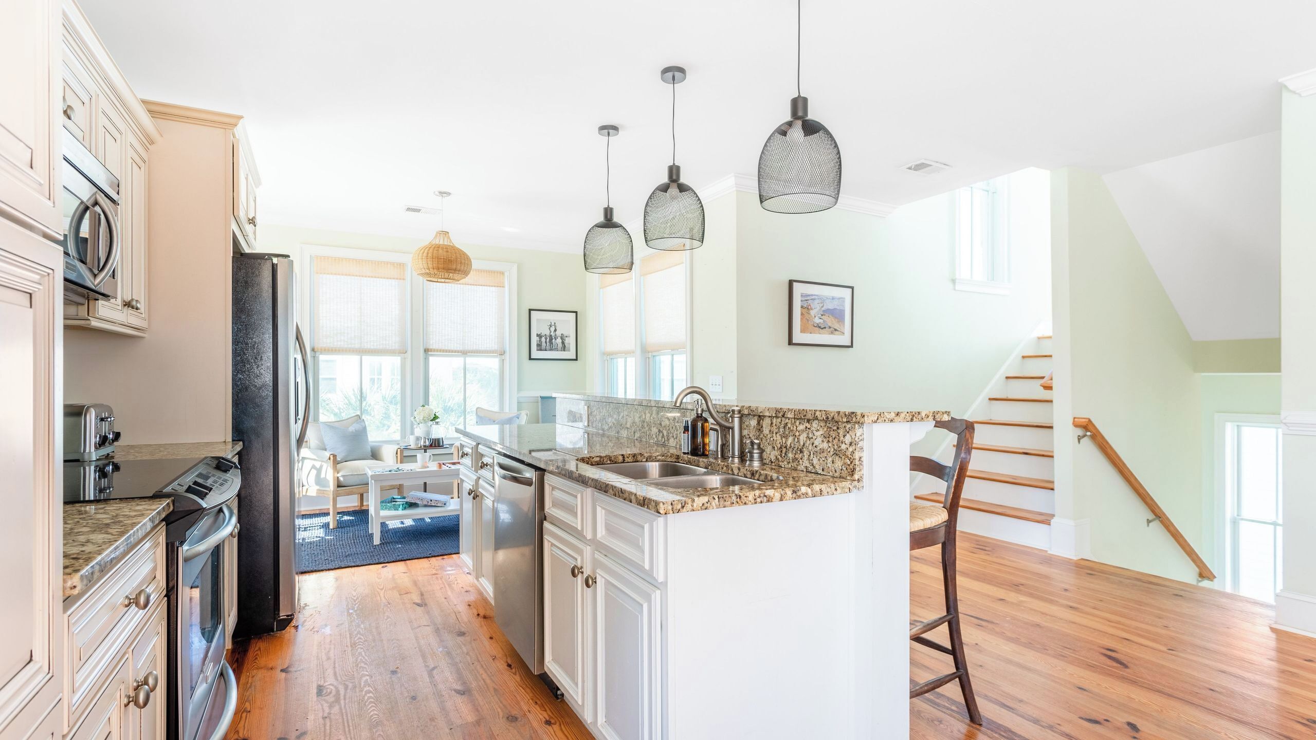 Una cocina con una isla central, zona de comedor y una escalera.