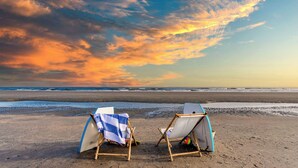 Two beach chairs with umbrellas on a sandy beach, facing the ocean. - Sea Shell by Avantstay Breezy Beachside Getaway w/ Rooftop Deck & 6 BRs (Isle of Palms)