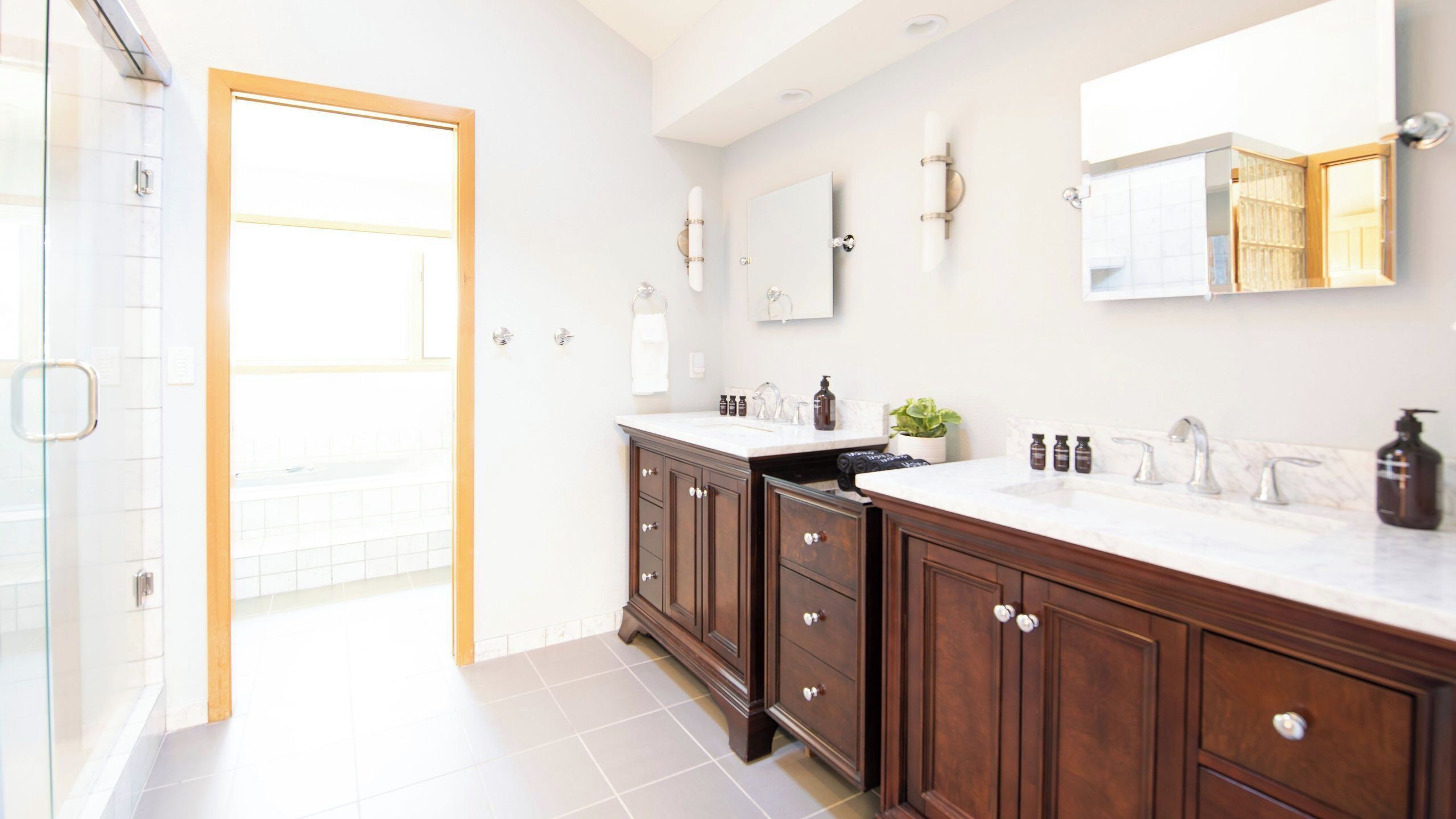 Un baño moderno con un espejo grande, una ducha y un lavamanos con gabinetes.