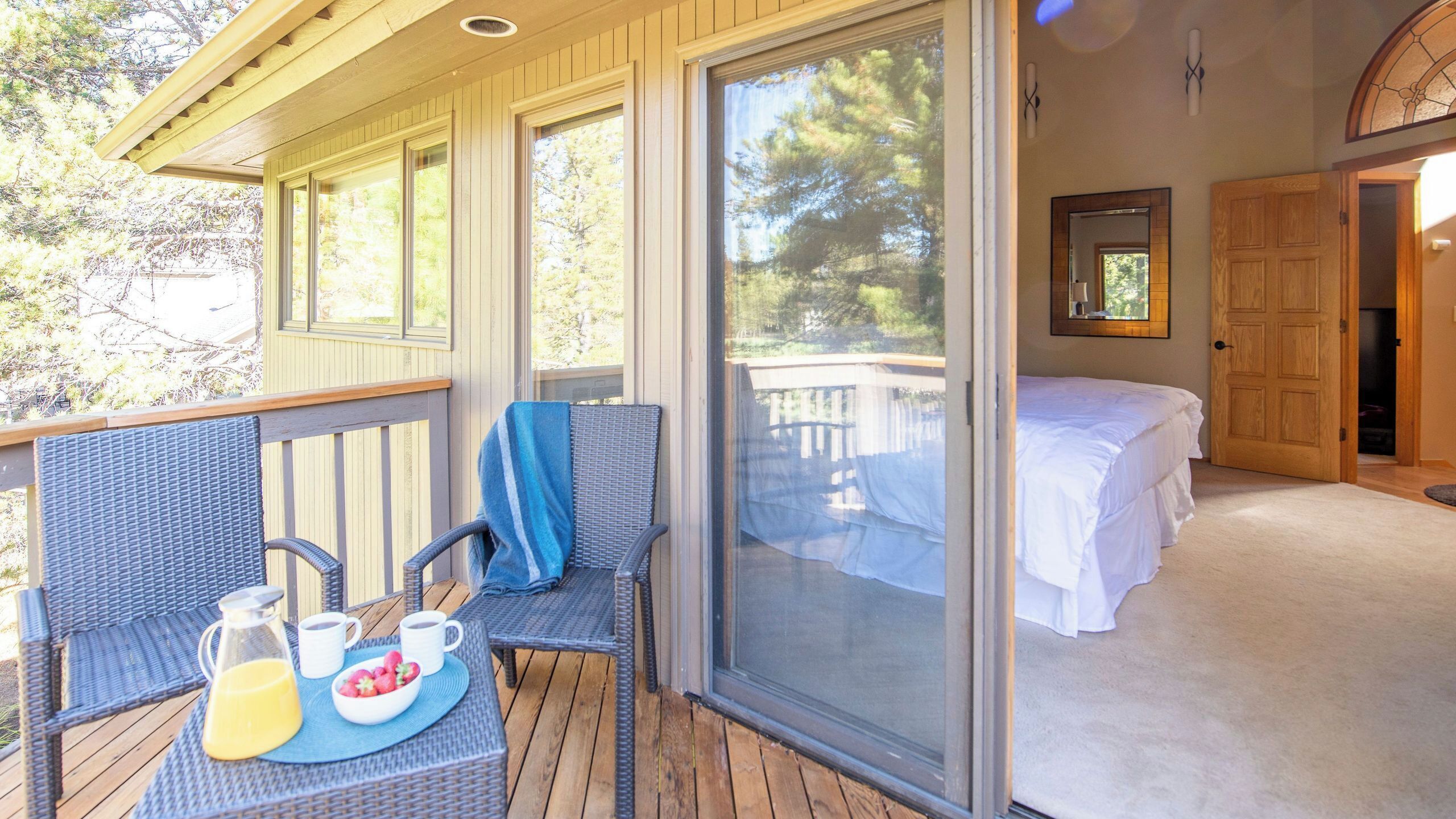 A room with a bed, a dining area with a table and chairs, and a sliding glass door leading to an outdoor deck.