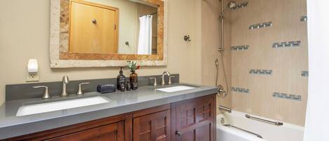 A bathroom with two sinks, a large mirror, wooden cabinets, and a walk-in shower.