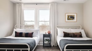 A bedroom with two beds, a nightstand, a window with curtains, and a framed picture on the wall. - Shelton & Urban by Avantstay Sleeps 20! 2 Unit Buyout! Spacious Design (Nashville)