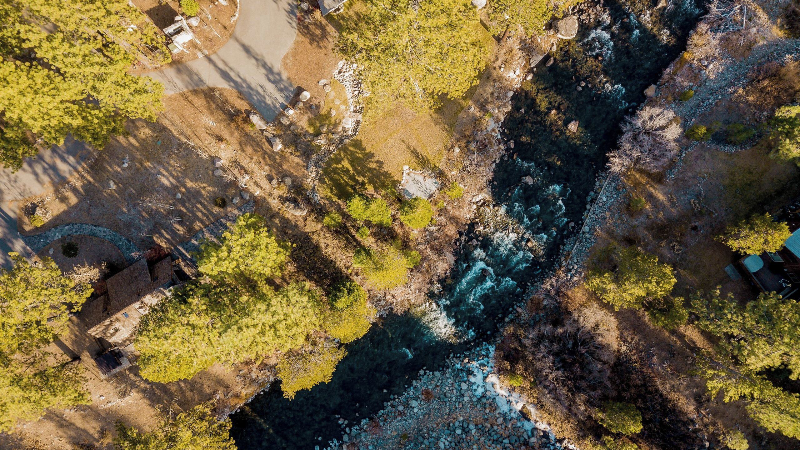 Une vue aérienne d’un paysage naturel comprenant une rivière, des arbres et un petit bâtiment.
