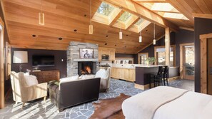 A spacious living area with a fireplace, wooden ceiling, and stone flooring.