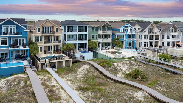 A coastal residential area with multi-story houses featuring balconies, a swimming pool, and a boardwalk. - Oceanfront, Pool+hot Tub, Game Room, Views Steps to Beach Lido by Avantstay (Hilton Head Island)